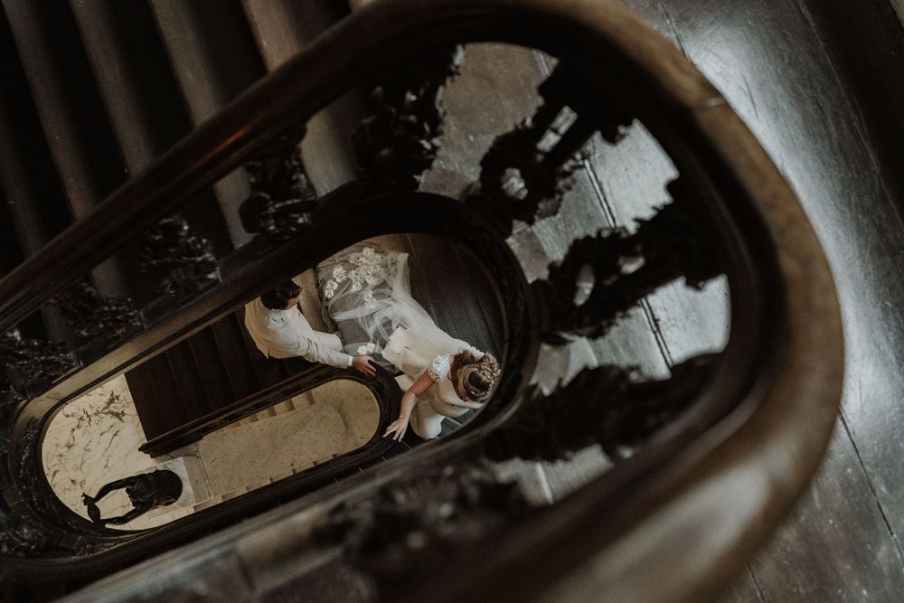 Looking down into a dark spiral staircase with vintage metal railings and worn stone steps.