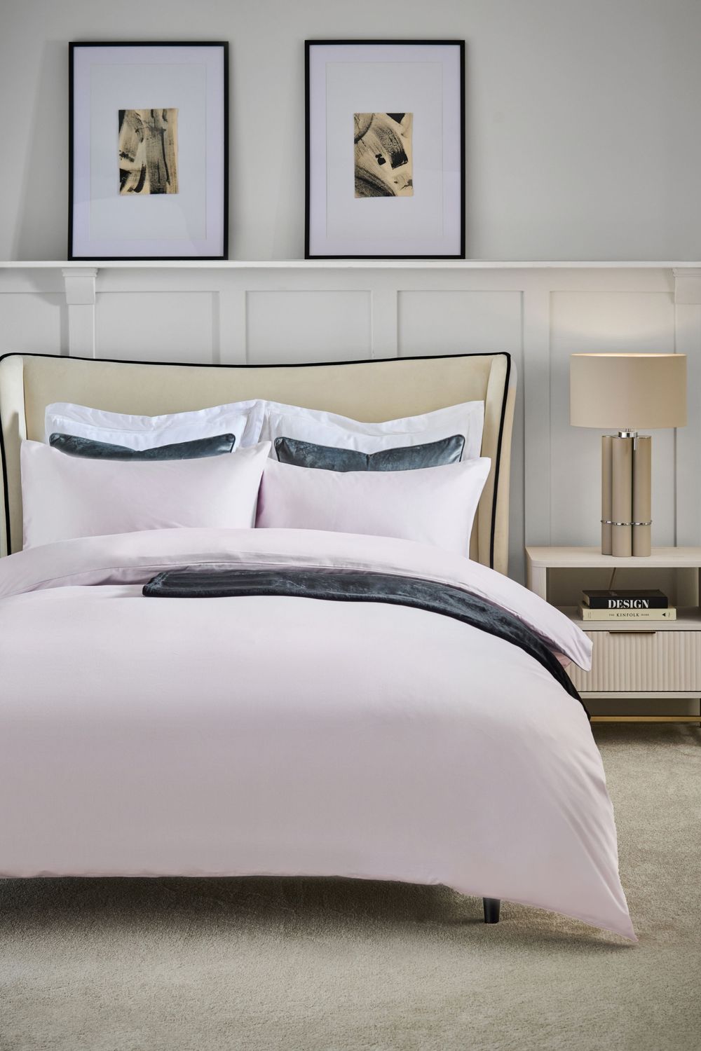 Contemporary bedroom featuring crisp white bedding with charcoal accents, framed abstract art, and modern nightstand with table lamp.