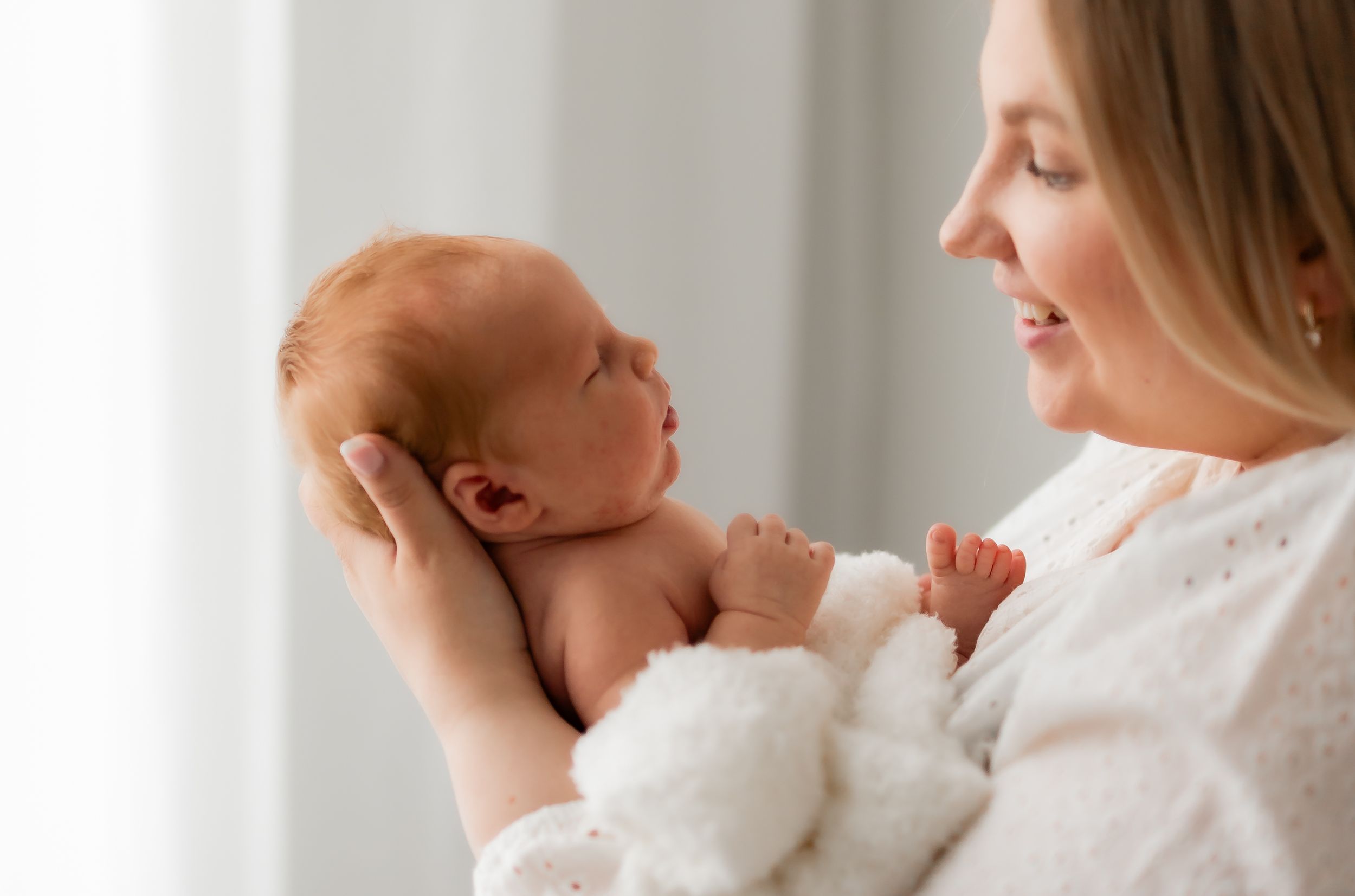 äiti pitelee vastasyntynyttä vauvaansa ja on todella onnellinen, rakkaudentäyteinen kuva newborn kuvauksesta