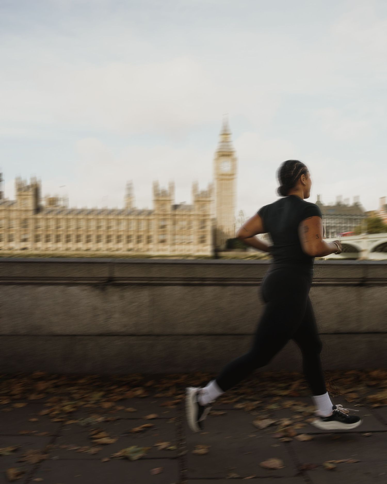 Person jogging along the Thames embankment with Big Ben and Houses of Parliament in the background, London.