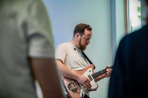 Nahaufnahme eines dunkelhaarigen Mannes, der Bass spielt auf einer Bühne.