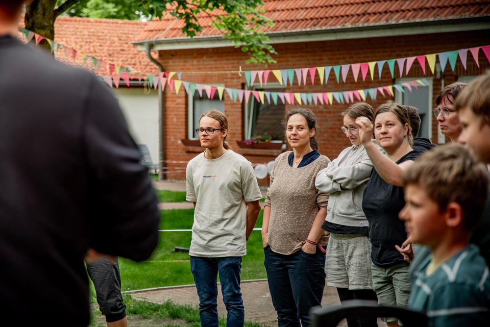 Menschen stehen im Grünen unter einer bunten Wimpelkette