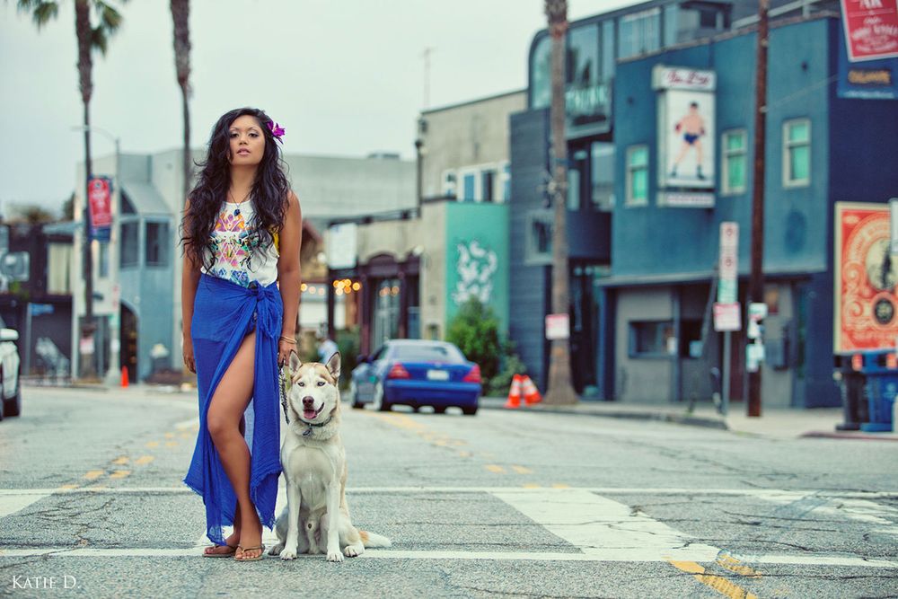 Young woman in blue skirt walks a Husky dog on a urban street in Los Angeles.