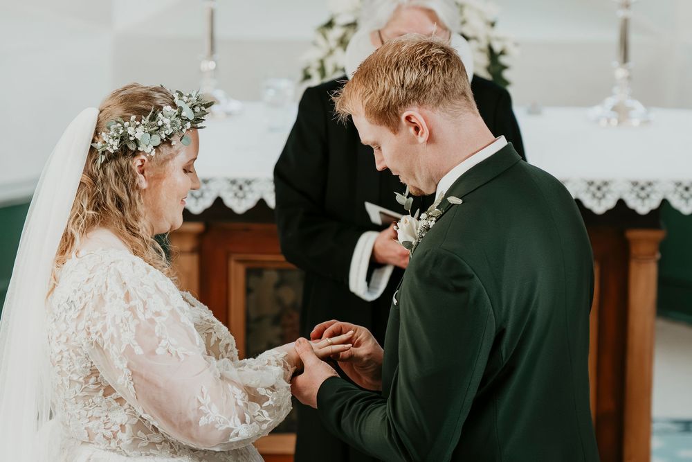 A bride and groom share an intimate moment during their wedding ceremony in a rustic church setting.
