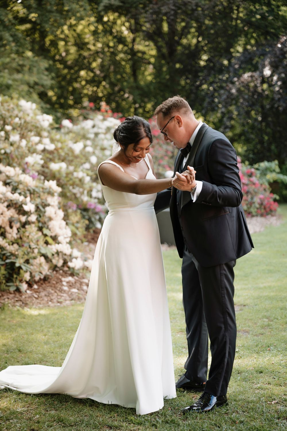 Wedding couple shares intimate moment in blooming garden setting.