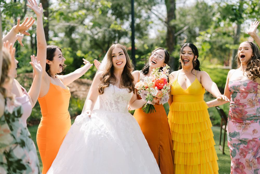 Calabasas, California. Joyful bride in white ball gown celebrating with bridesmaids in colorful dresses outdoors.