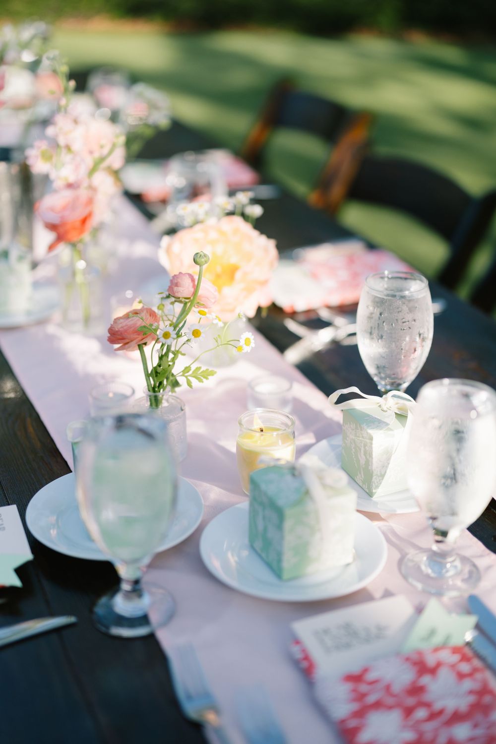 Elegant outdoor wedding reception table with pink florals, candles, and pastel place settings. Beautiful wedding table set up