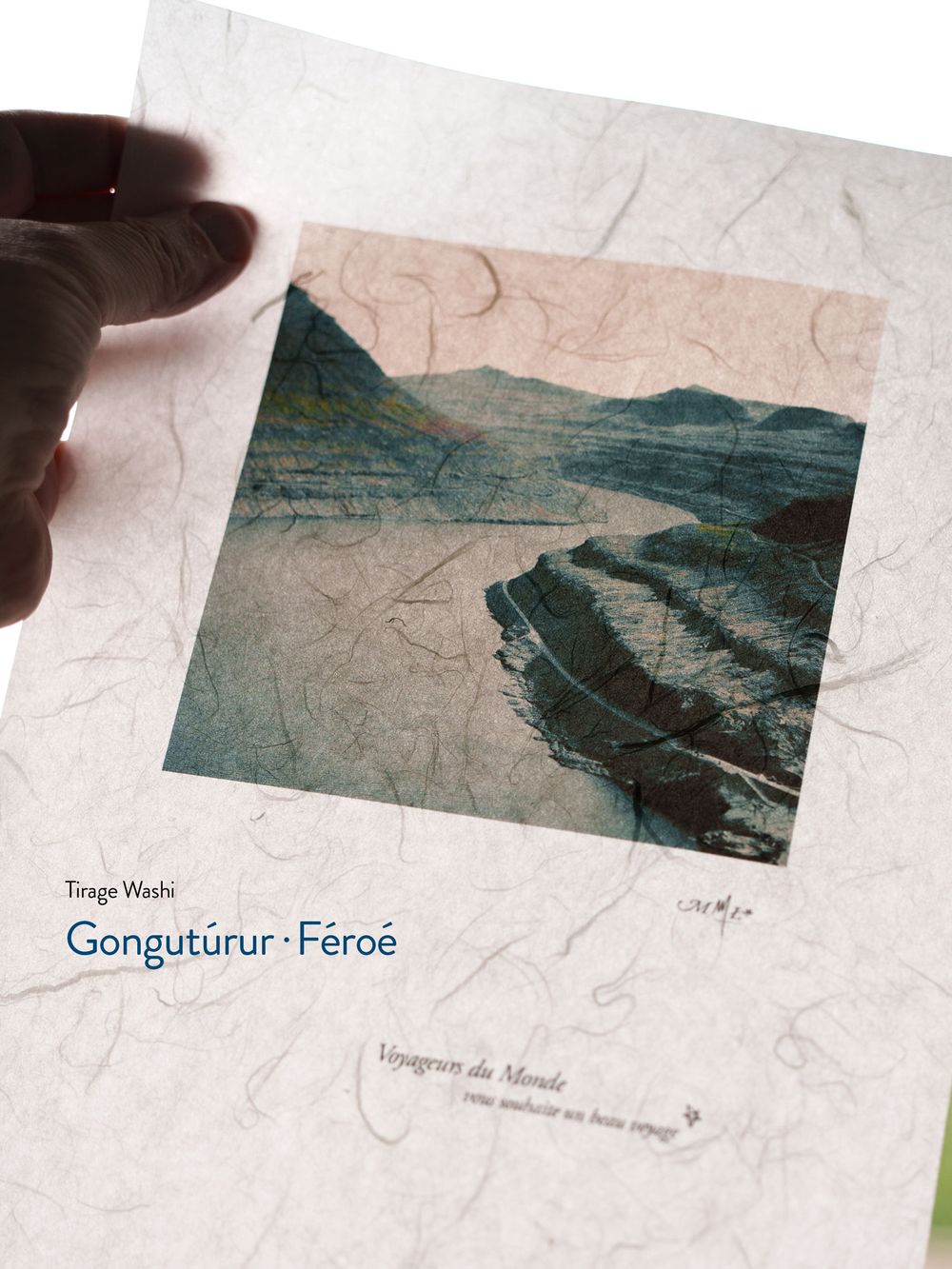 Hand holding a Washi print book titled Gongutúrur Féroé, featuring a scenic Faroe Islands landscape photograph on the cover.