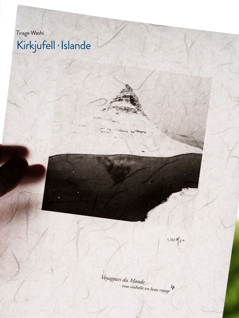 Hand holding a washi print of Kirkjufell mountain in Iceland, featuring delicate textured paper and minimalist ink illustration.
