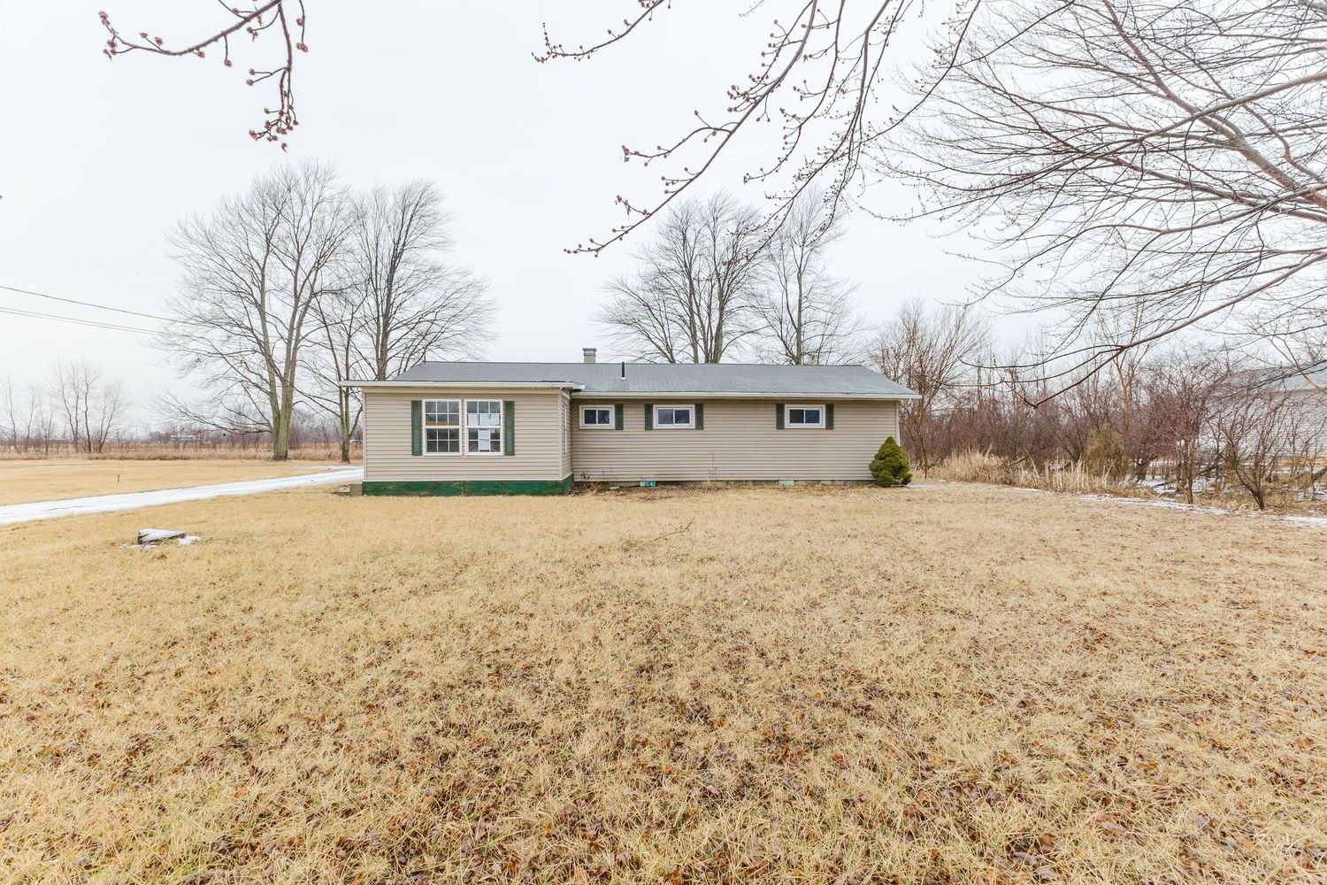 Classic white clapboard bungalow with covered front porch, brick accent wall, and detached garage on a corner lot.