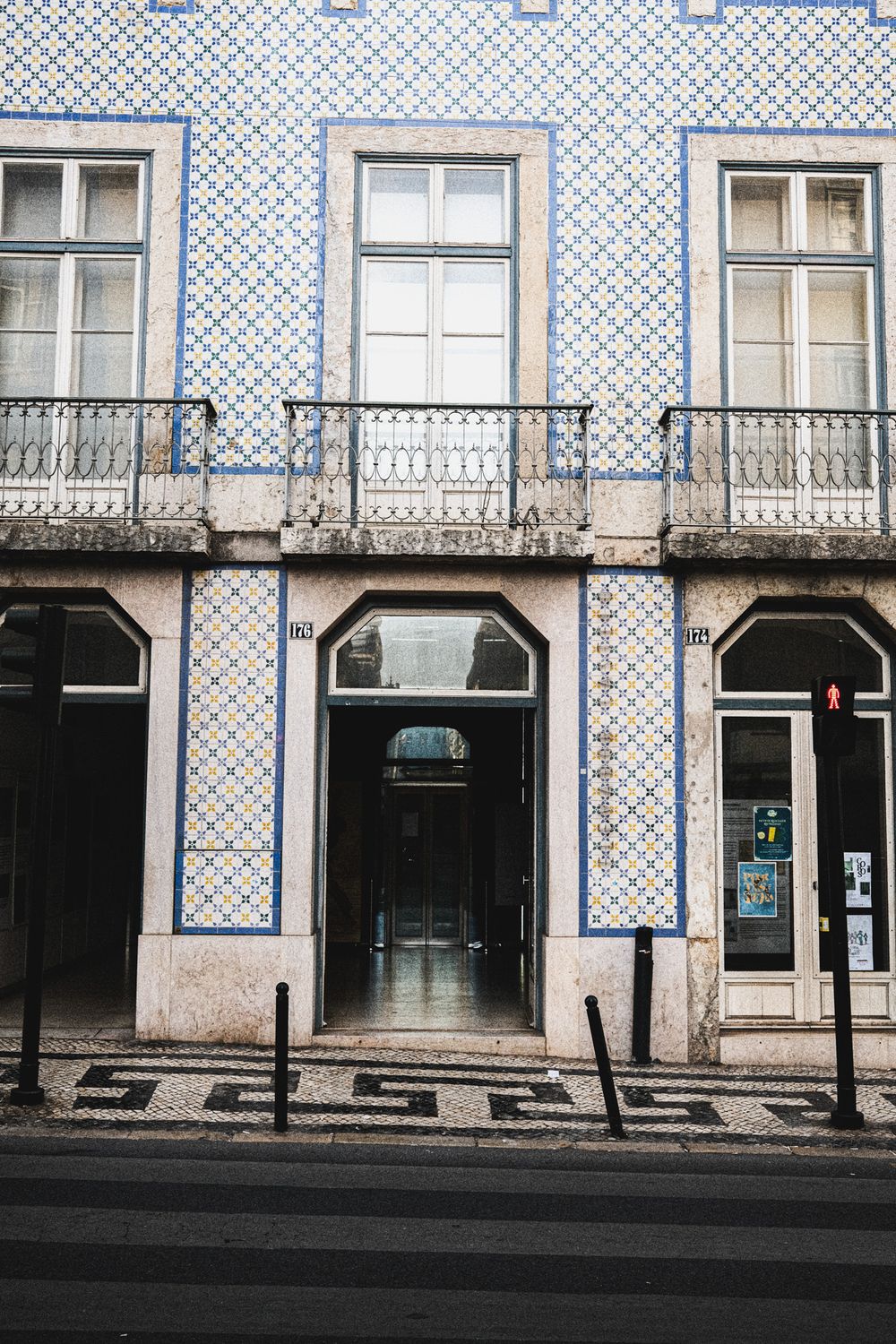 Traditional Portuguese building facade with blue and white azulejo tiles, wrought iron balconies, and arched doorway in Lisbon.