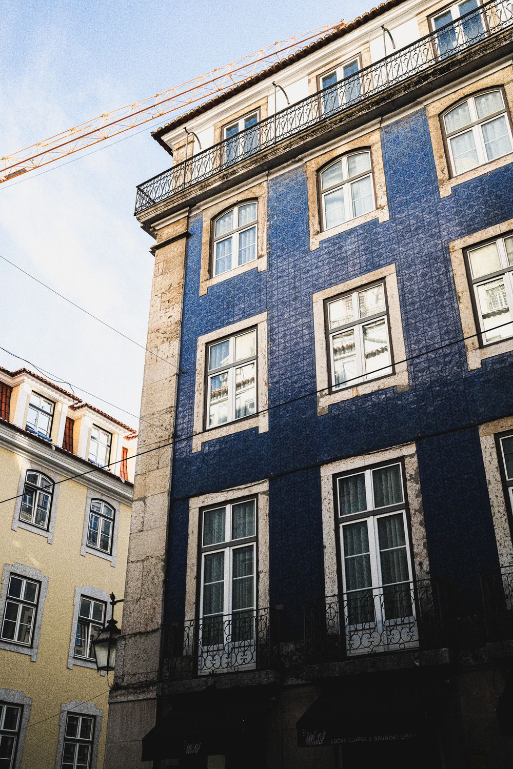 Blue azulejo-tiled building facade with white-framed windows in historic Lisbon, Portugal.