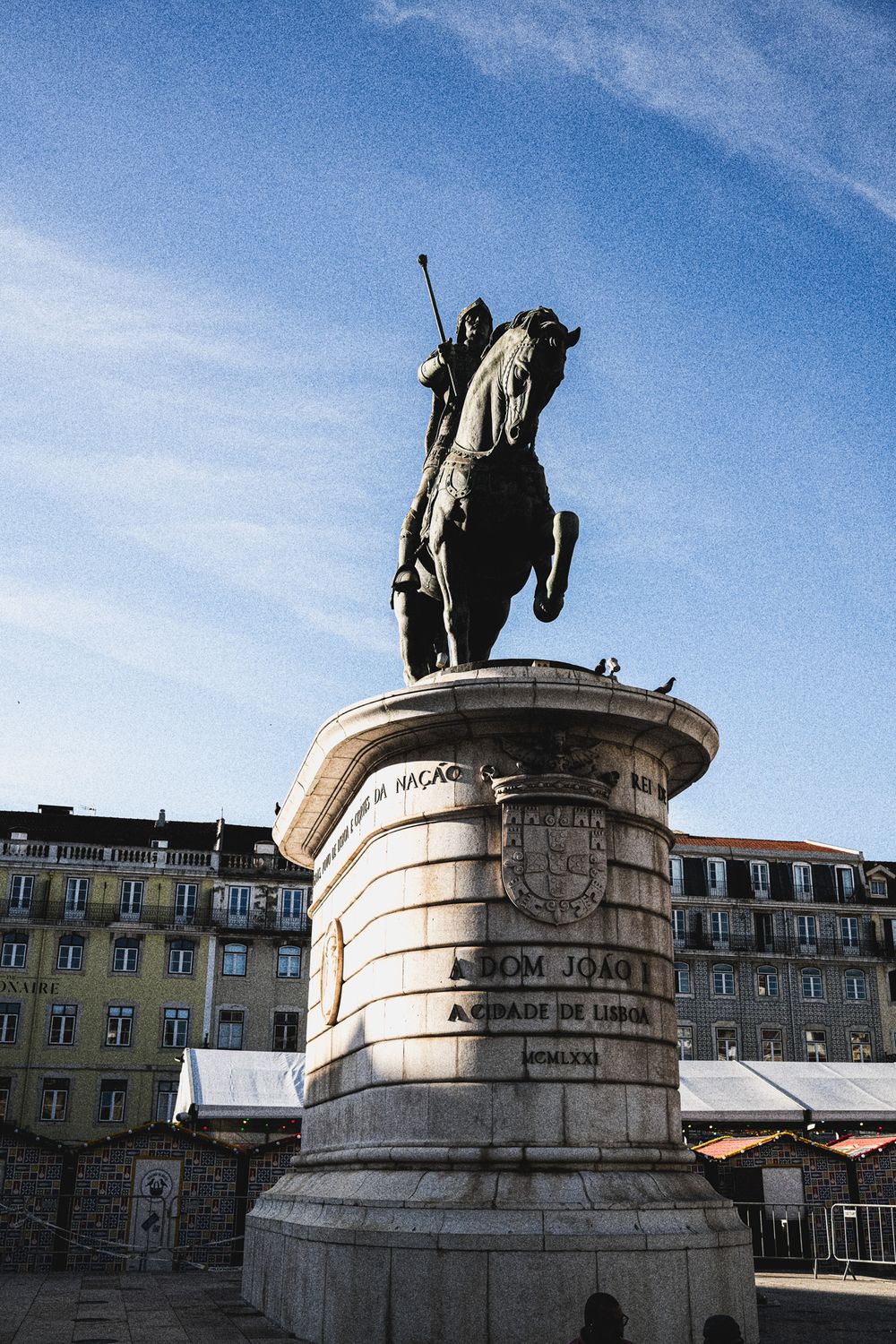 Equestrian statue of Dom João I on a stone pedestal in Lisbon, Portugal, against a blue sky.