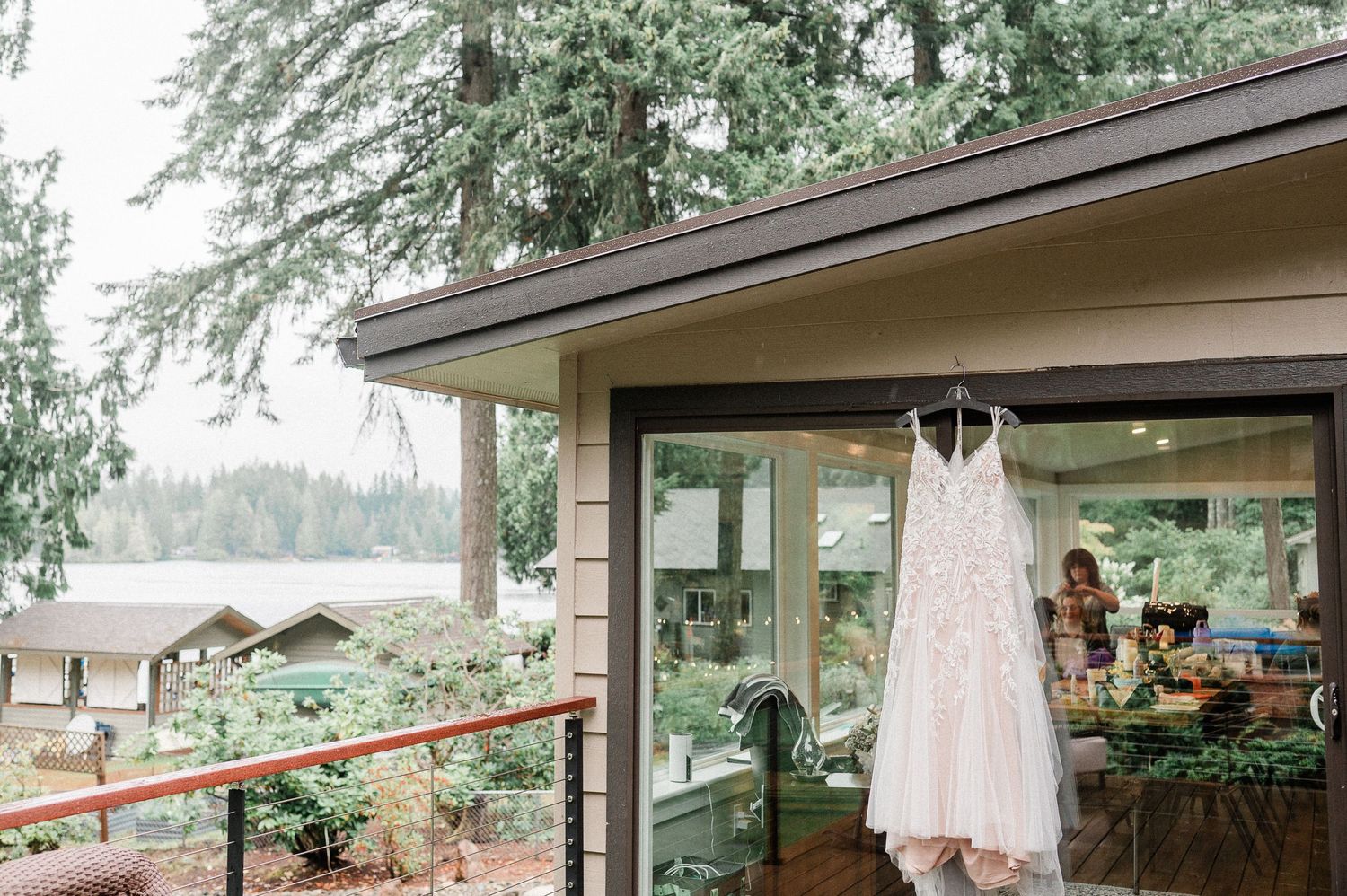 White lace wedding dress hanging outside a modern cabin with forest and lake views in the Pacific Northwest.