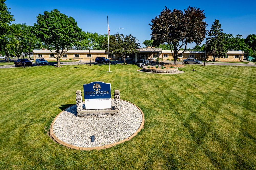 Edenbrook senior living facility with manicured green lawn, and single-story brick building under clear blue sky. branding photoshoot
