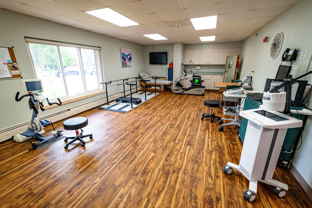 Modern physical therapy gym with hardwood floors, exercise equipment, parallel bars, and bright lighting. branding photography