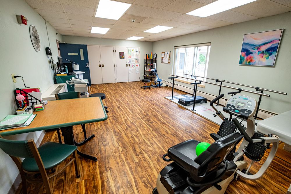 Bright physical therapy room with hardwood floors, parallel bars, exercise bike, and treatment tables in a modern clinic. branding photoshoo