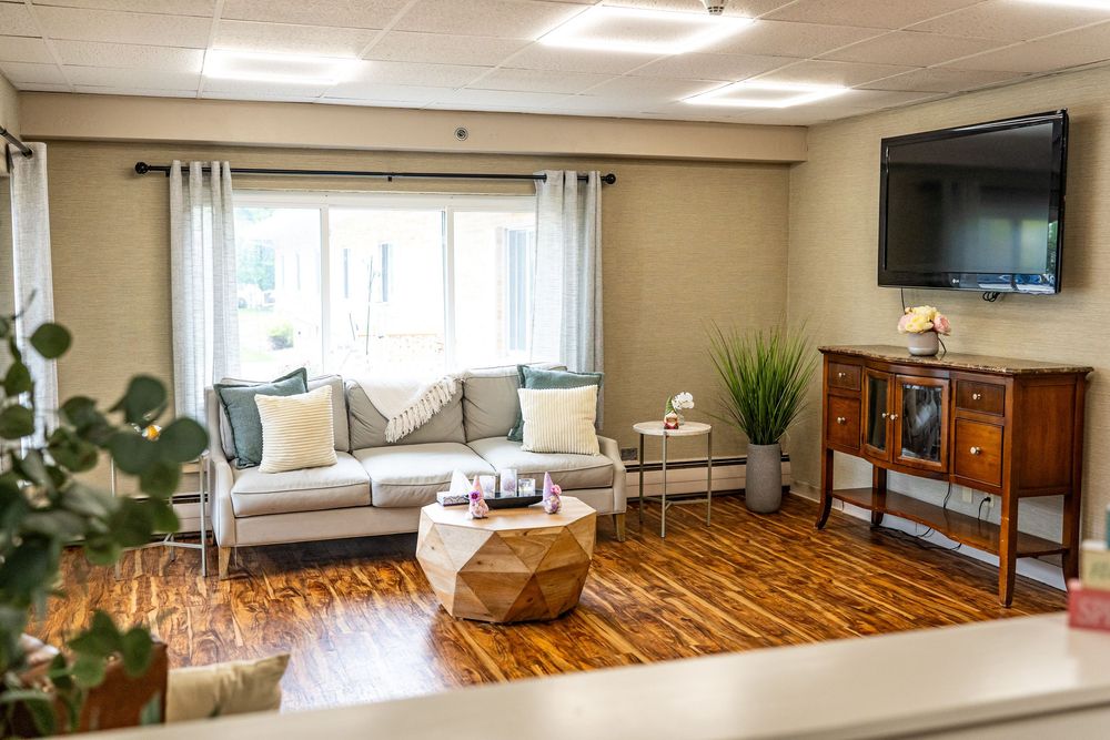 Modern living room with gray sofa, wood coffee table, hardwood floors, and wall-mounted TV in a bright, cozy space. interior photography