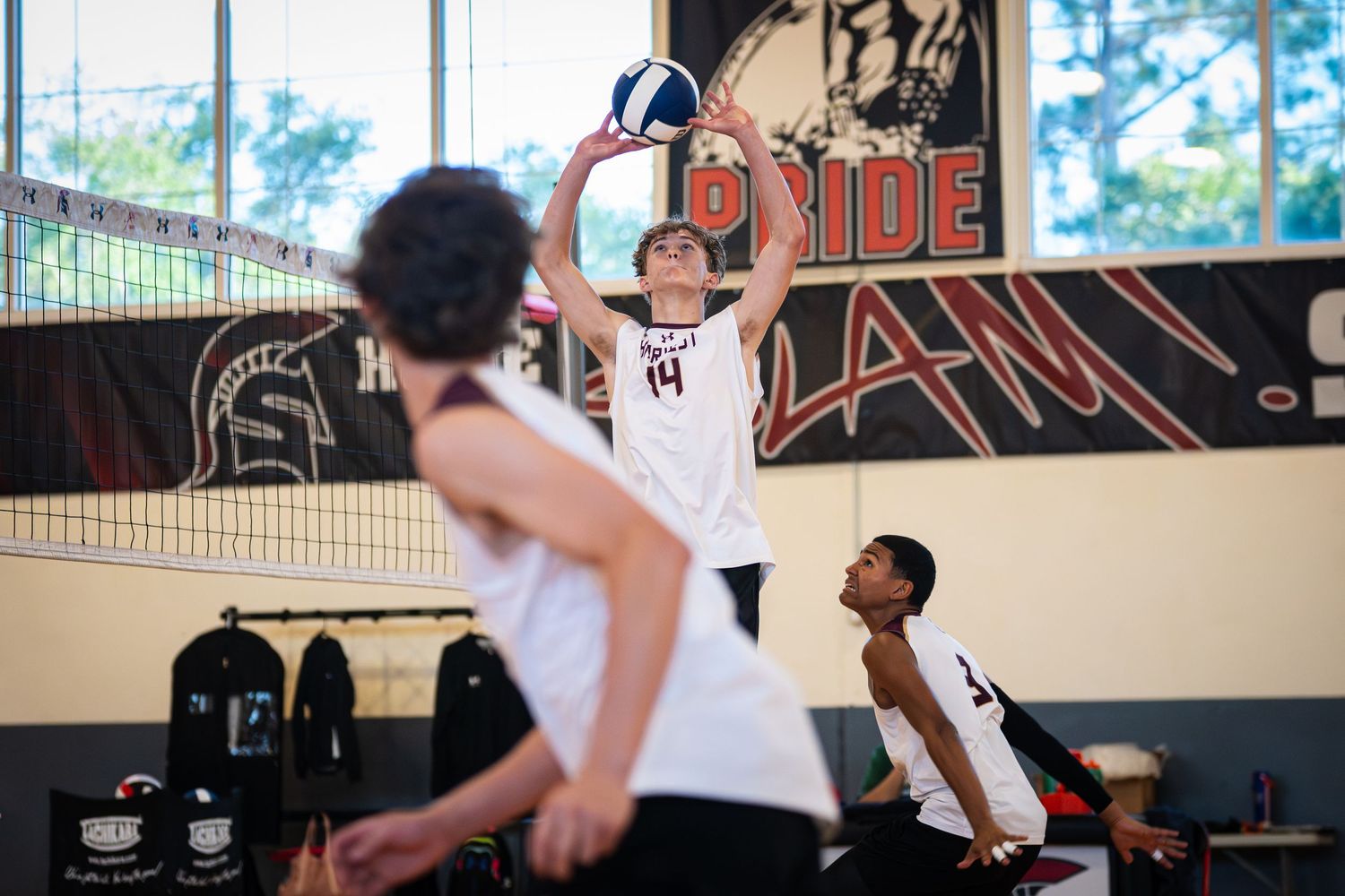 Female volleyball player in red uniform performing a dig during an indoor volleyball match.