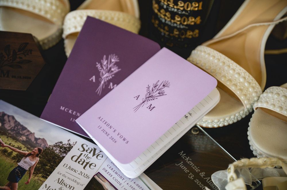 Purple wedding passports and save the date cards displayed with pearl heels and floral stationery.