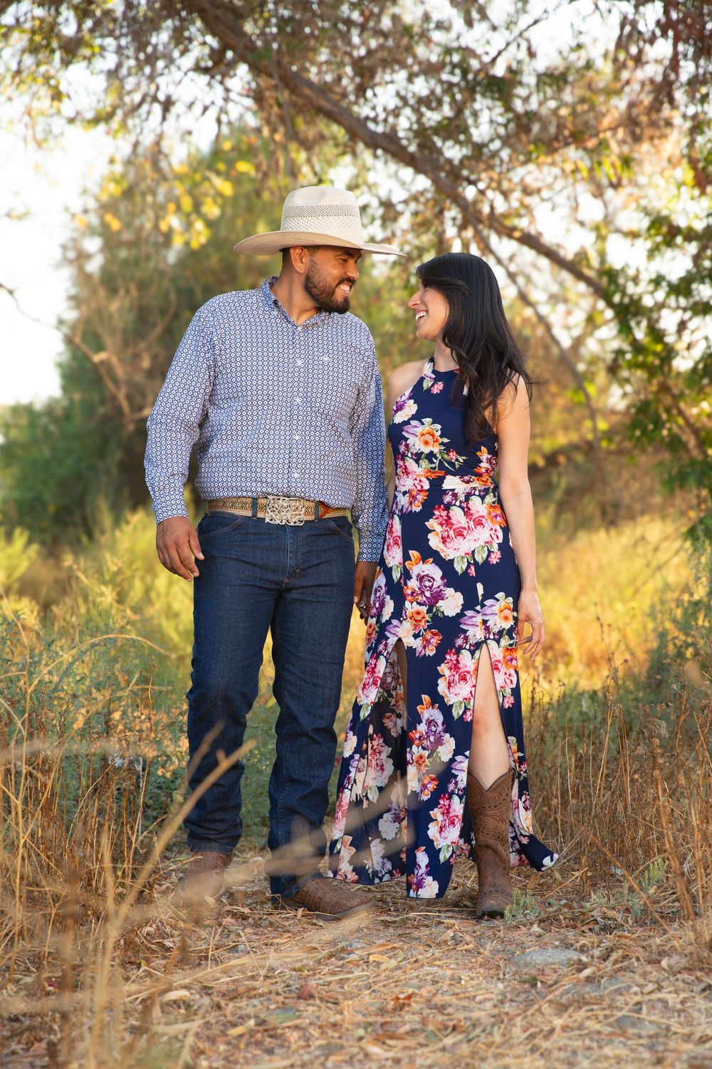 Engaged couple walking while holding hands and smiling at one another