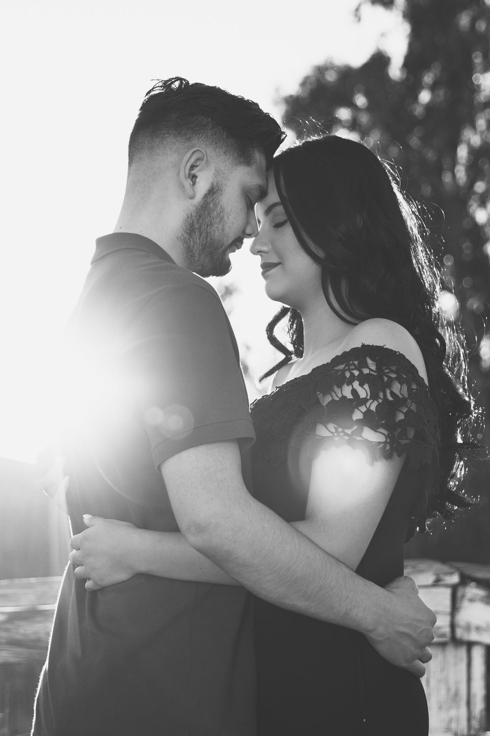Black and white photo of couple embracing one another while their foreheads touch