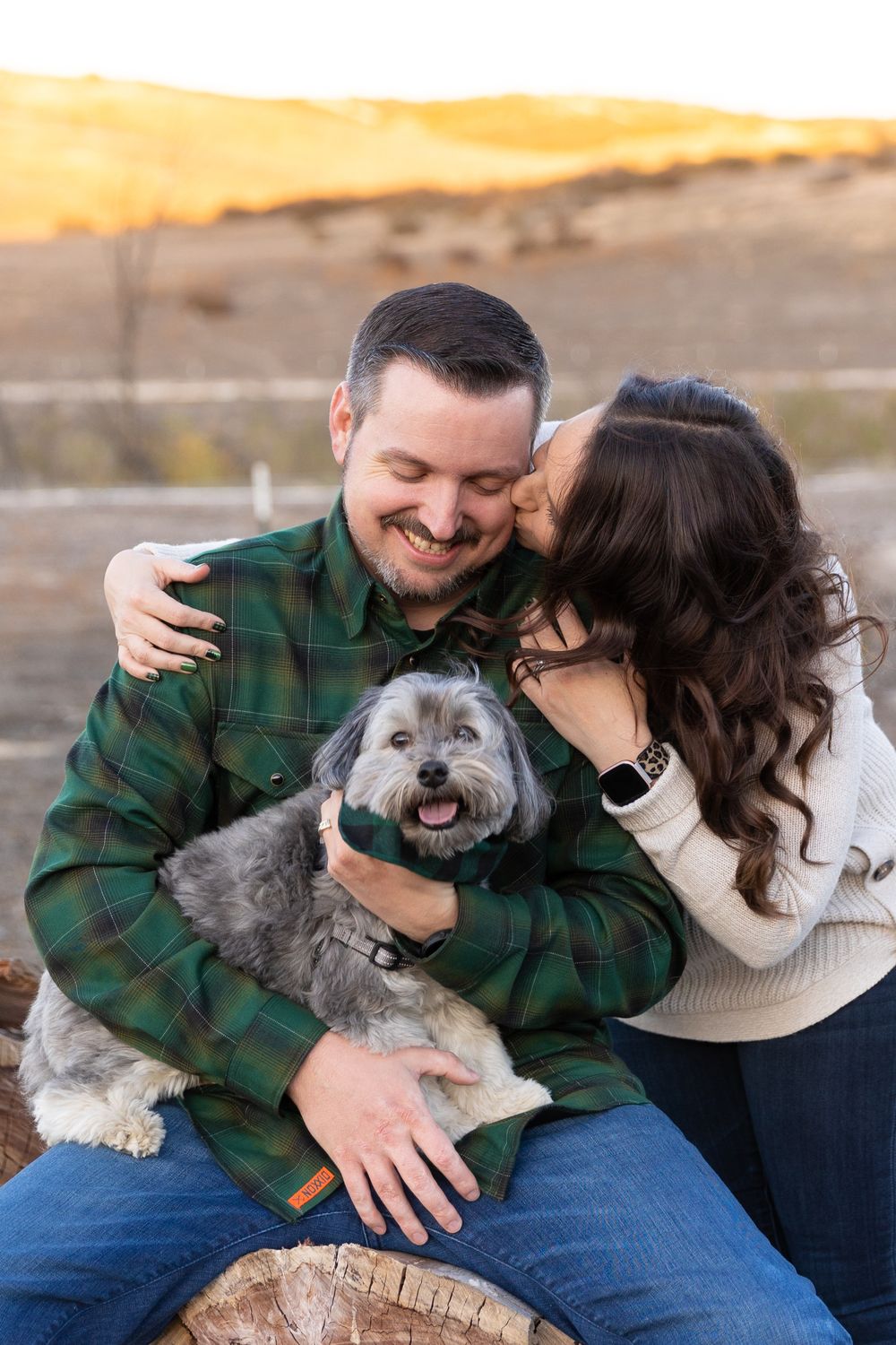Couple holding each other while smiling down at their dog