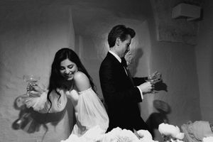 Black and white photo of a bride and groom toasting with champagne glasses at their elegant wedding reception.