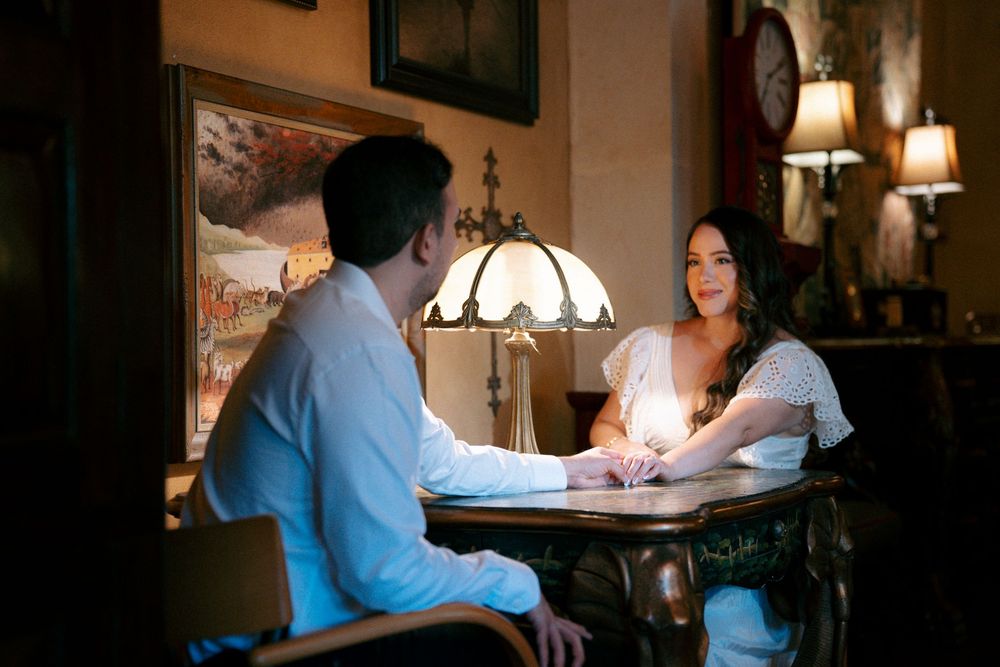 Couple sharing an intimate conversation at a dimly lit restaurant table with warm lamp lighting.