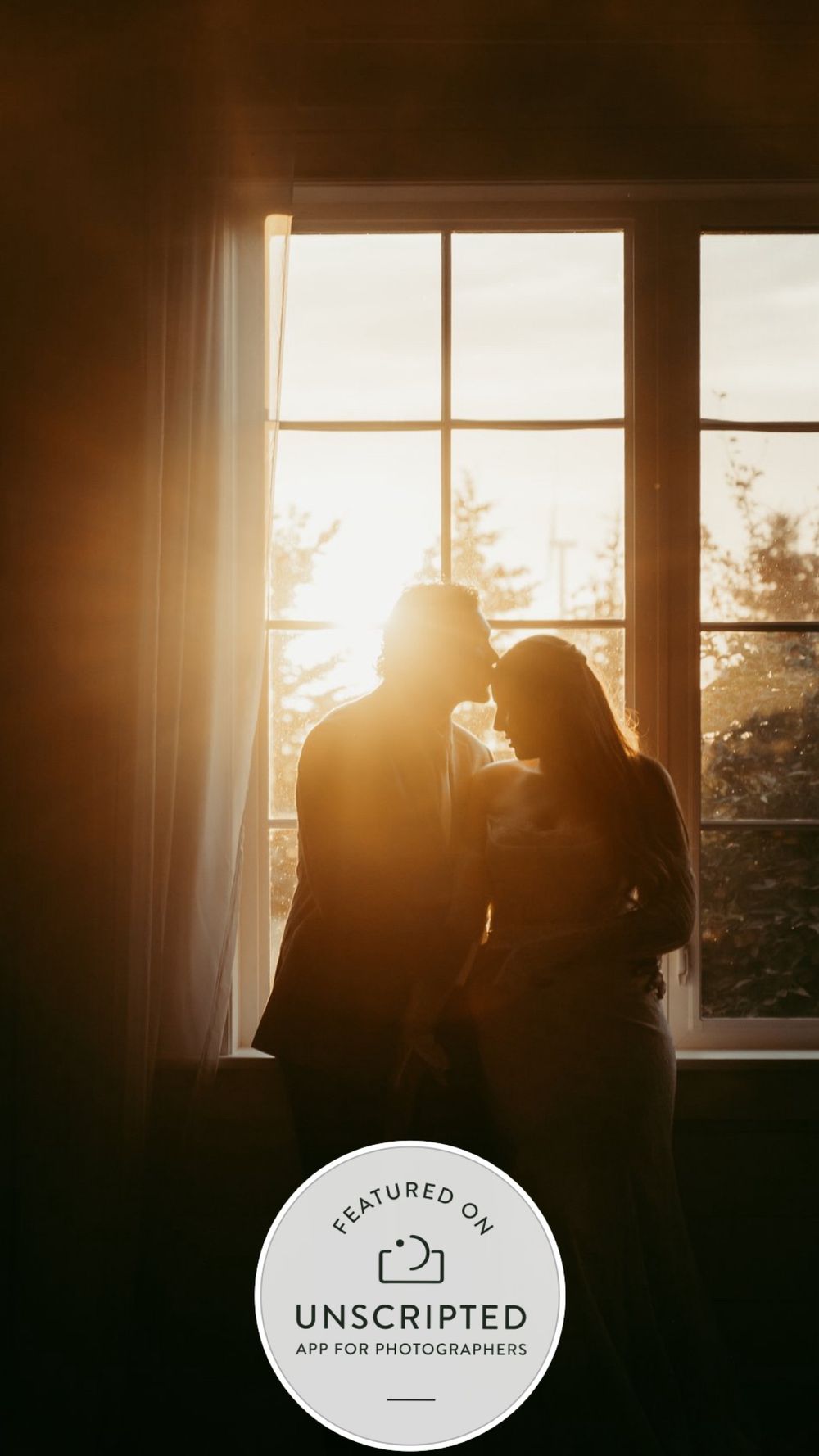 Silhouette of a romantic couple sharing an intimate moment by a sunlit window with warm golden light.