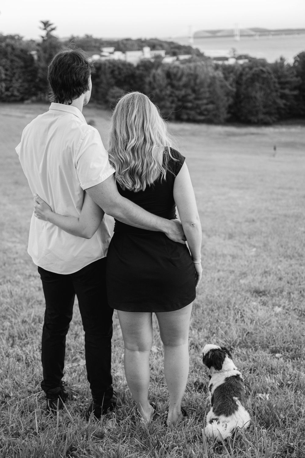 Couple and dog gazing at scenic landscape in black and white outdoor portrait photography.