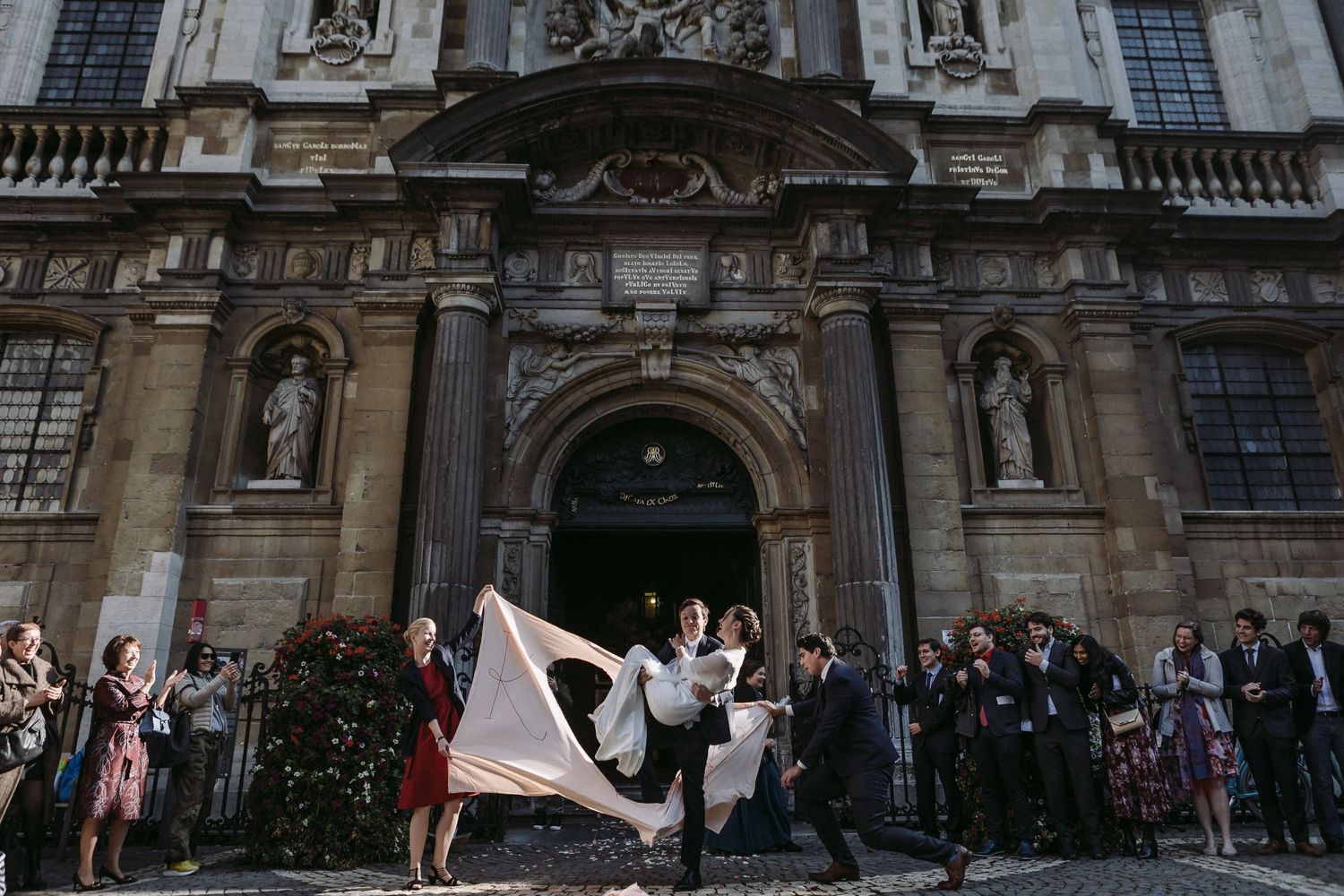 Wedding guests gathered outside historic church facade with celebratory flags.