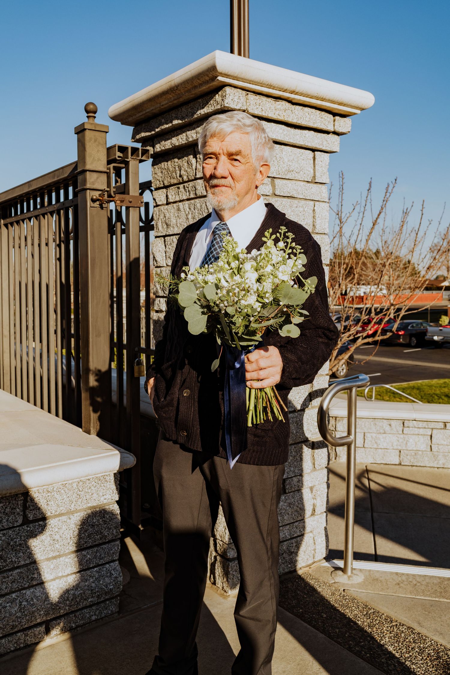 The grandfather to the bride holds her bouquet while waiting for her to be done with the ceremony
