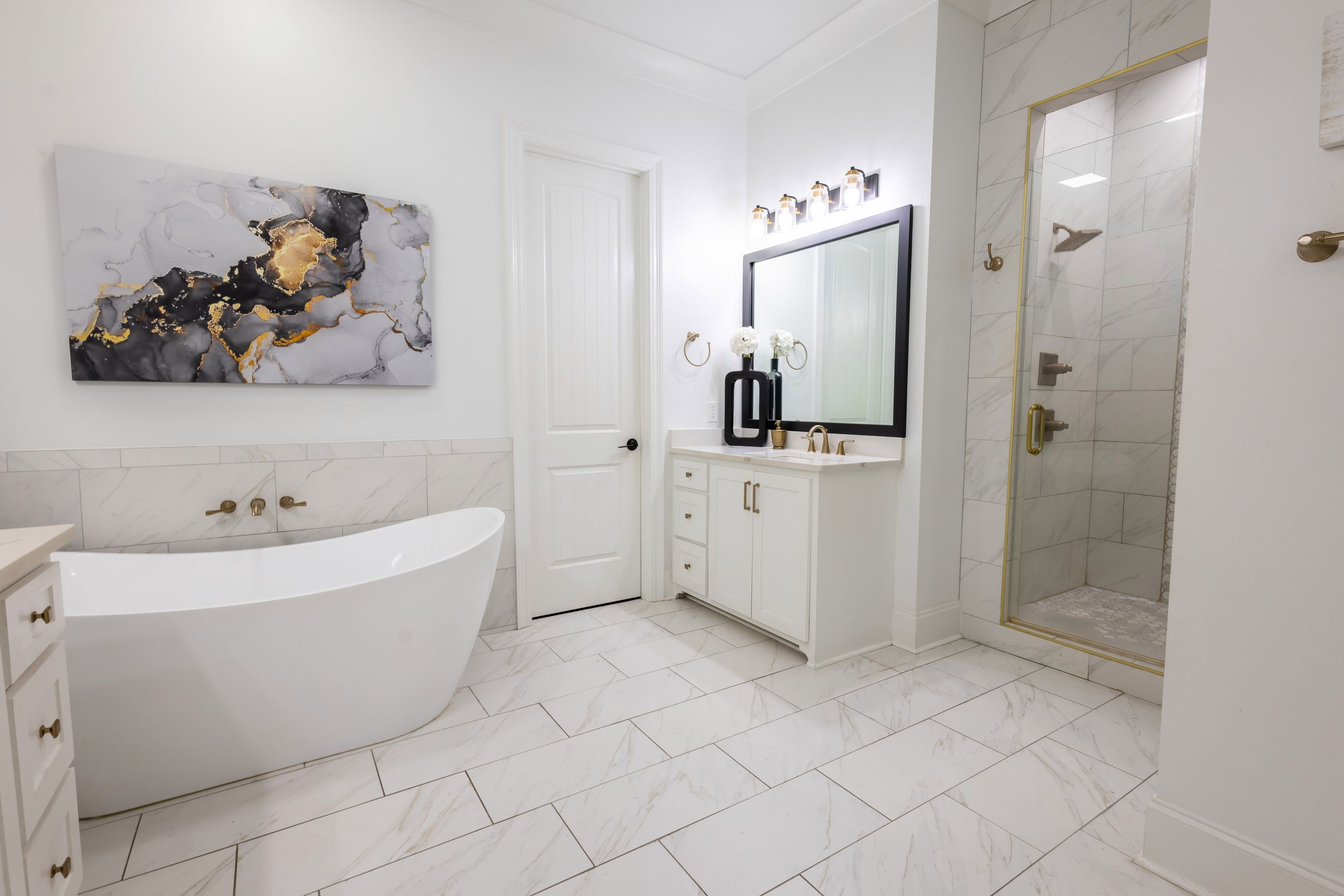 Luxurious white bathroom with freestanding soaking tub, abstract wall art, and marble tile flooring.