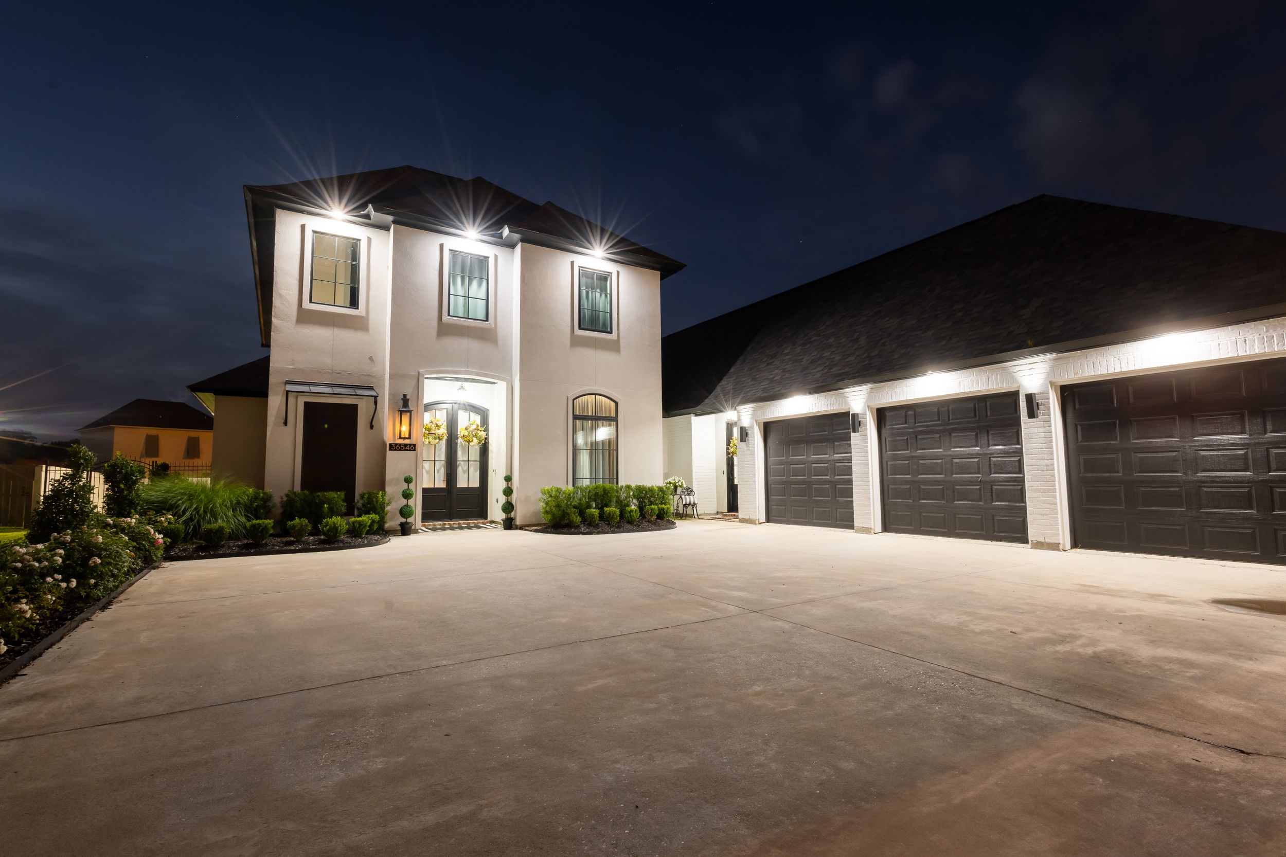 A series of exterior garage doors illuminated at night with bright white lighting against dark surroundings.