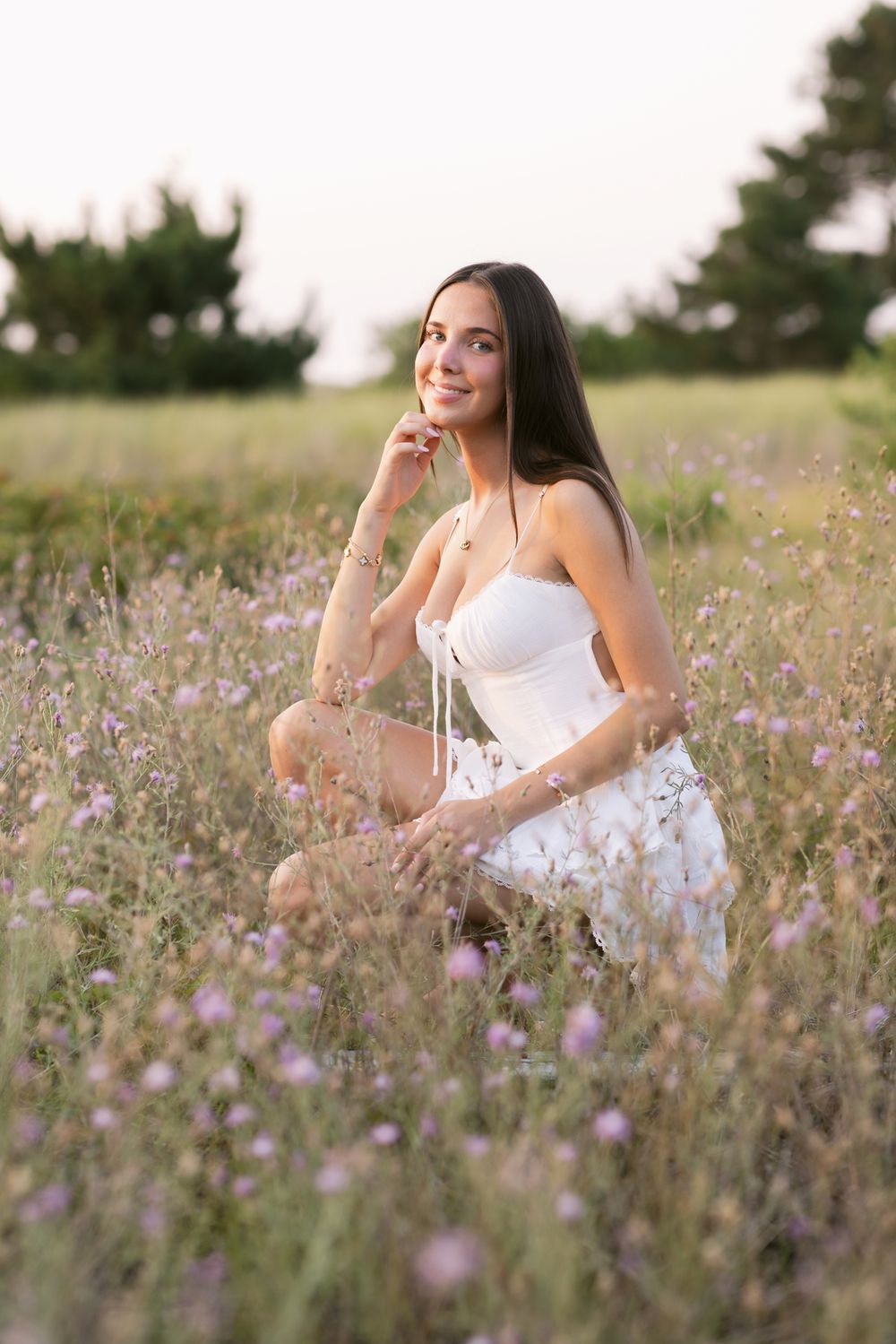 Senior girl wears short white dress standing in purple clover at Salisbury State Reservation New Hampshire. Lakes Region senior photographer
