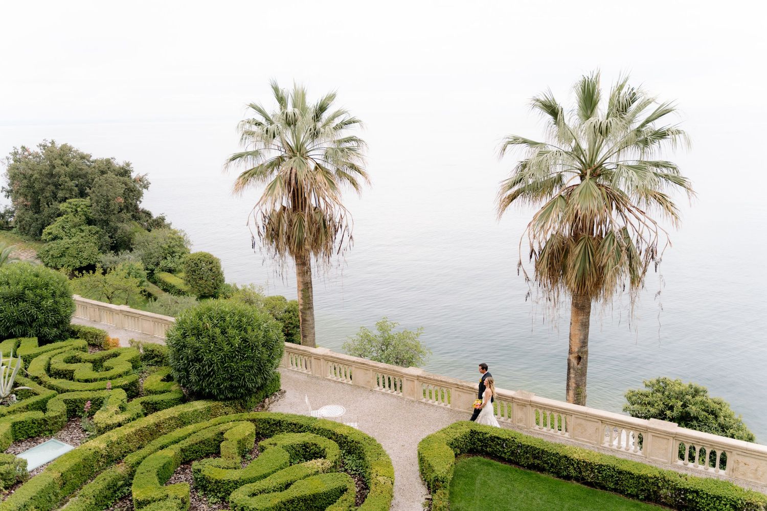 Bride and groom walking through the Italian gardens of Isola del Garda