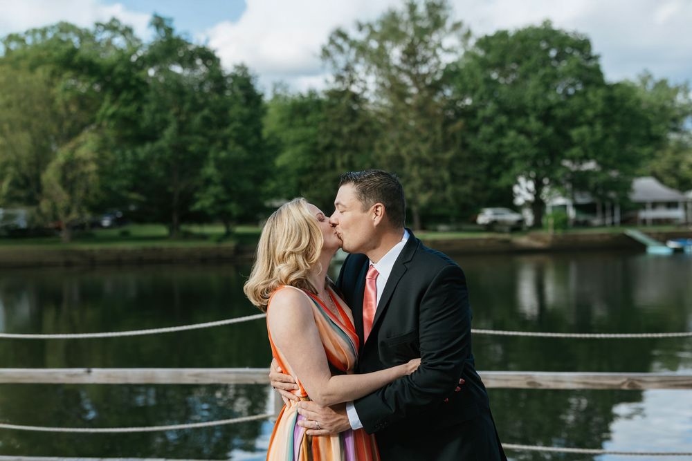 A romantic couple shares tender moments by a serene lake during their engagement photo session at sunset.
