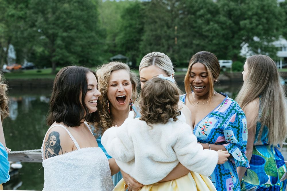 A group of people wearing blue and white outfits celebrate together outdoors near a lake.