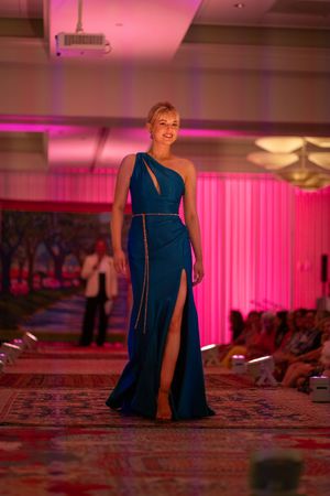 Model in a one-shoulder Camille's navy blue evening gown with thigh-high slit is showcased during the Azalea spring fashion show 2026