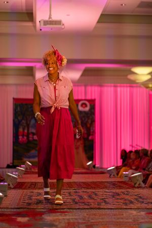 Tracey Newkirk wears a striped tied shirt and red culottes while walking down the runway at the Azalea spring fashion show 2026.
