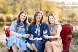 Group portrait of family members arranged on red vintage furniture in outdoor field.