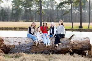Group sitting and standing on fallen tree logs in an outdoor nature setting.