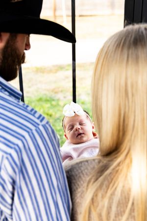 Close-up shots of parents holding their sleeping newborn in a bright indoor setting.