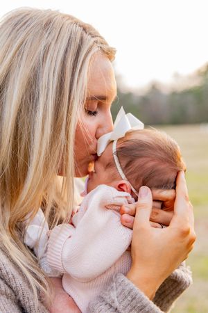Close-up shots of a mother giving gentle kisses to her newborn baby in soft lighting.