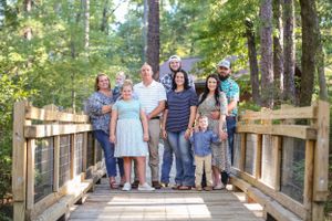 Family gathering on a wooden boardwalk surrounded by tall pine trees.