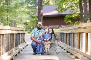 Natural light photography of a family on a wooden boardwalk surrounded by trees.