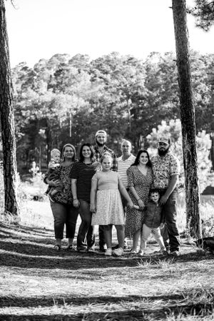 Group portrait taken on a pine-needle covered forest path in black and white.