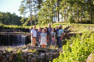 Family portrait session at a scenic outdoor location with stone walls and lush greenery.