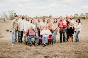 Large group portrait taken in a rustic field setting under cloudy skies.
